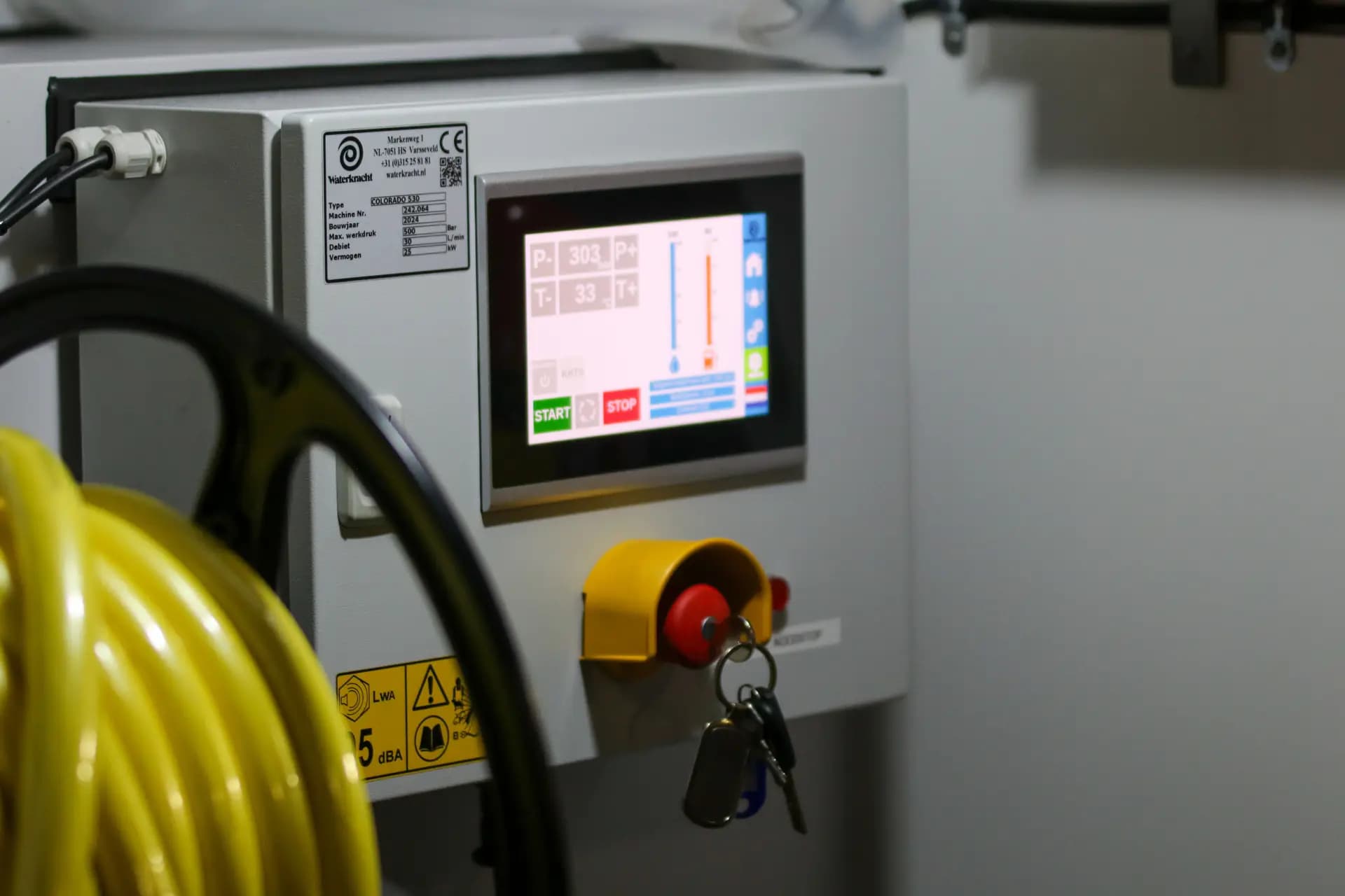 Colour touchscreen panel mounted beside an emergency stop button on an industrial machine