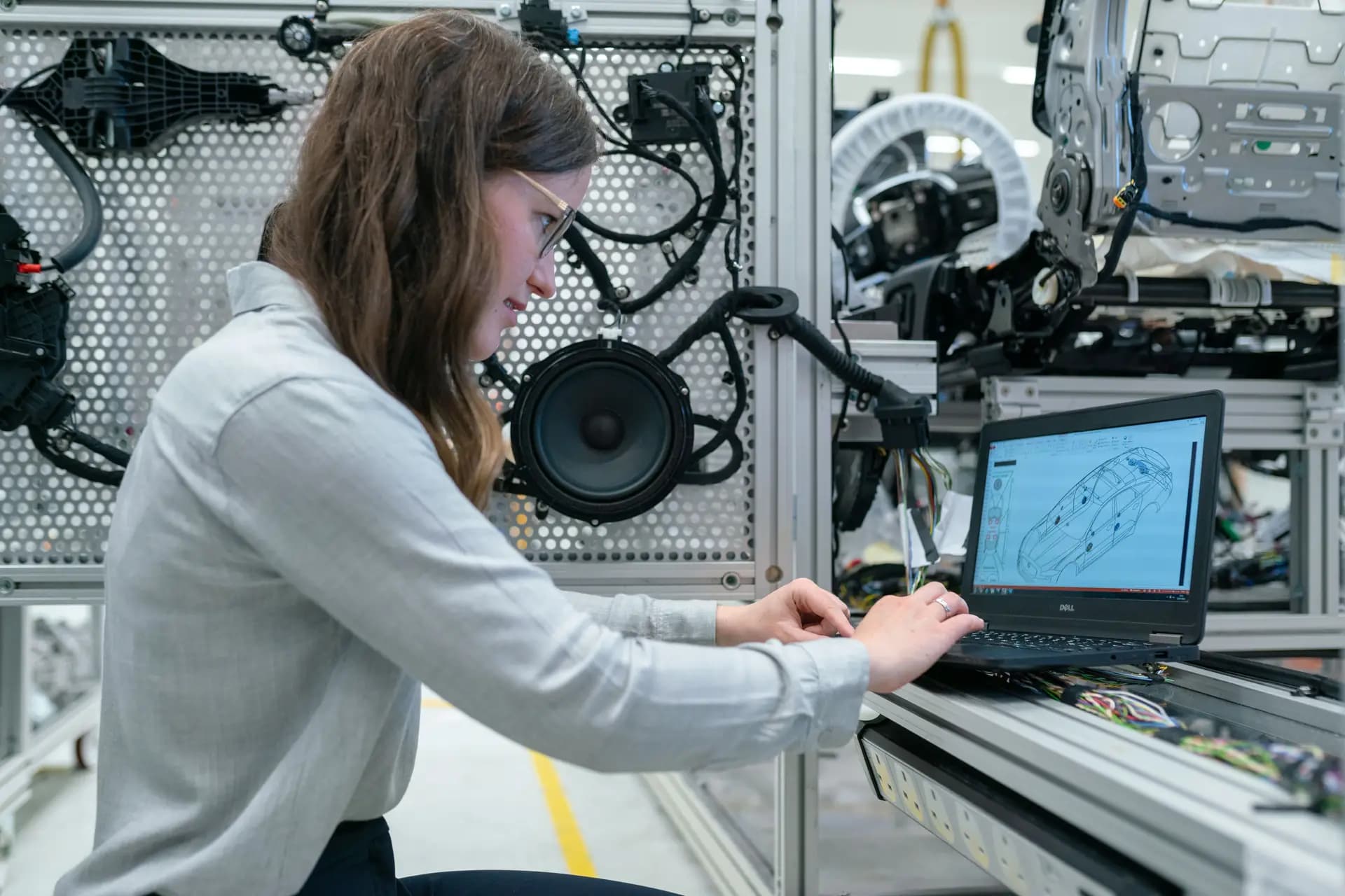Woman engineer working on a laptop connected to a mechatronics test rig