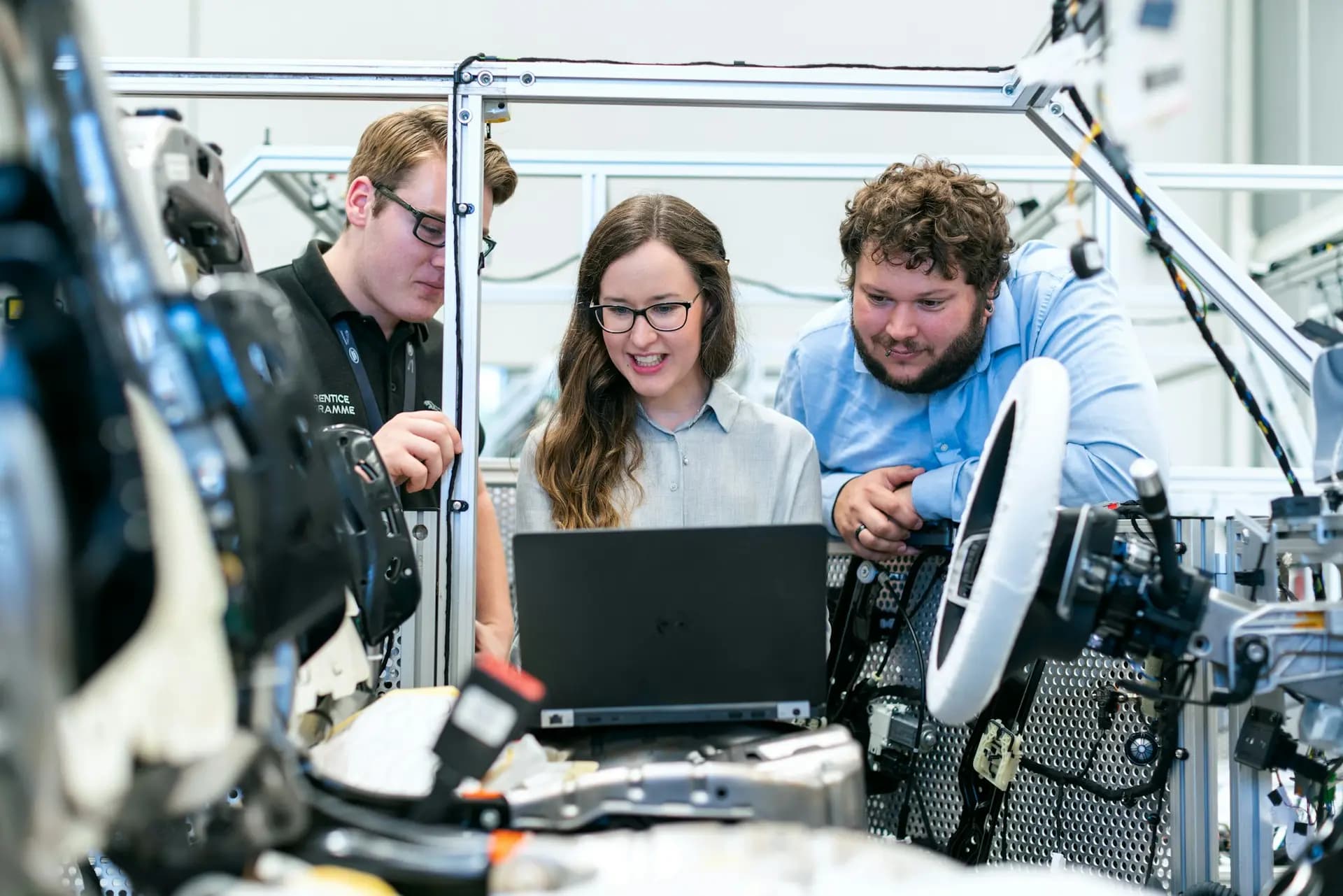 Three engineers looking at a laptop in an automation workshop