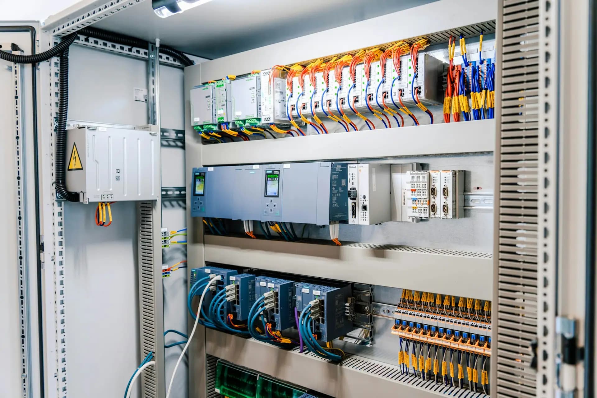 Open industrial control panel with PLC modules, terminals and wiring