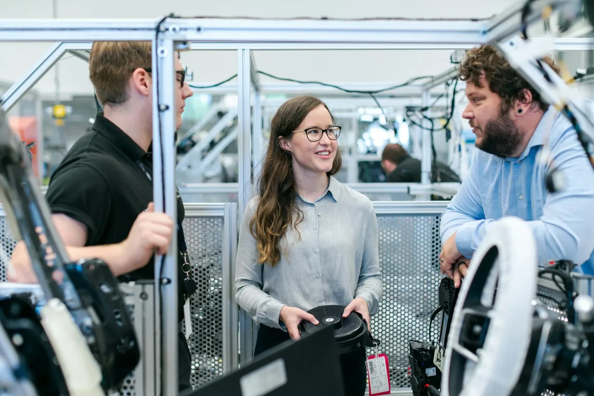 Engineers talking beside an automation test rig, one looking up and smiling
