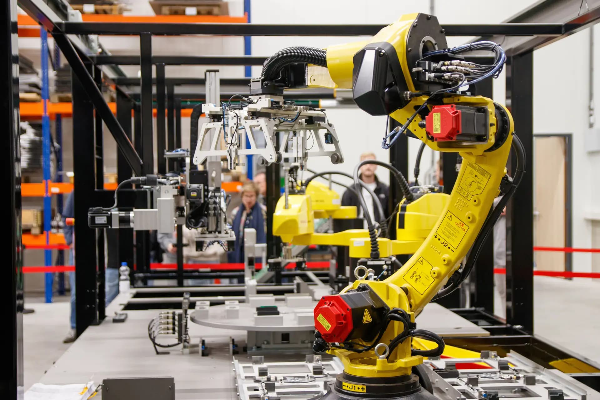 Yellow industrial robot arms working inside an automated production cell