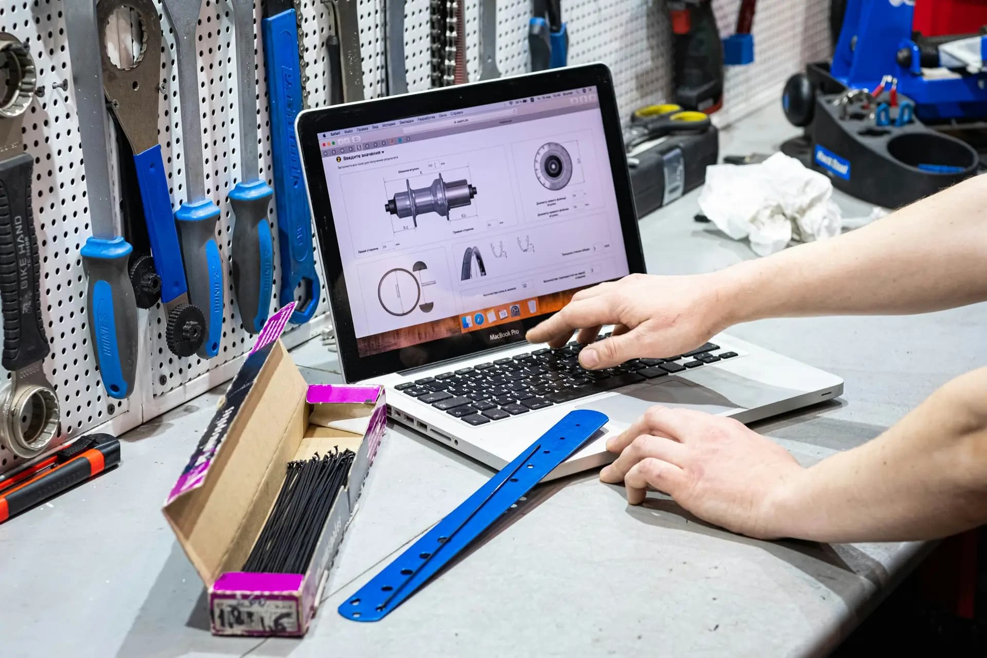 Engineer working on a laptop at a workbench surrounded by tools