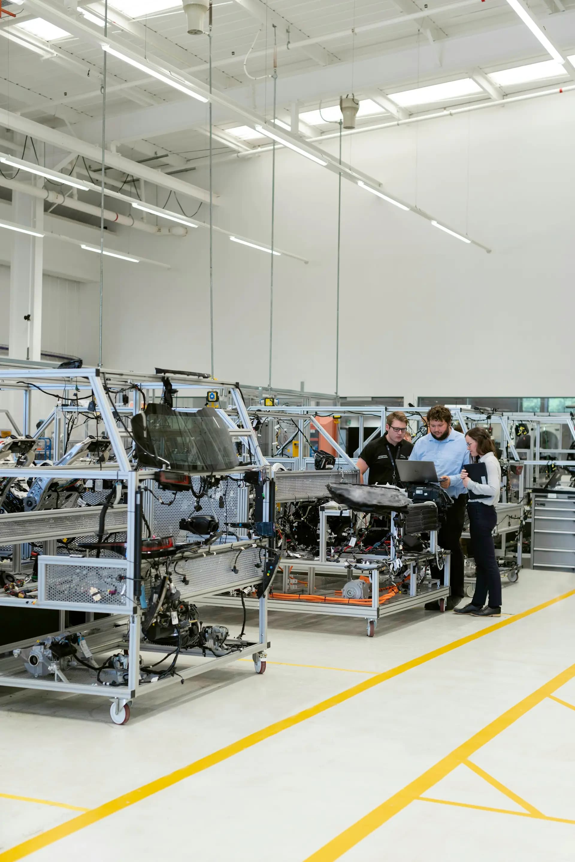 Engineers reviewing a laptop beside an automated assembly line