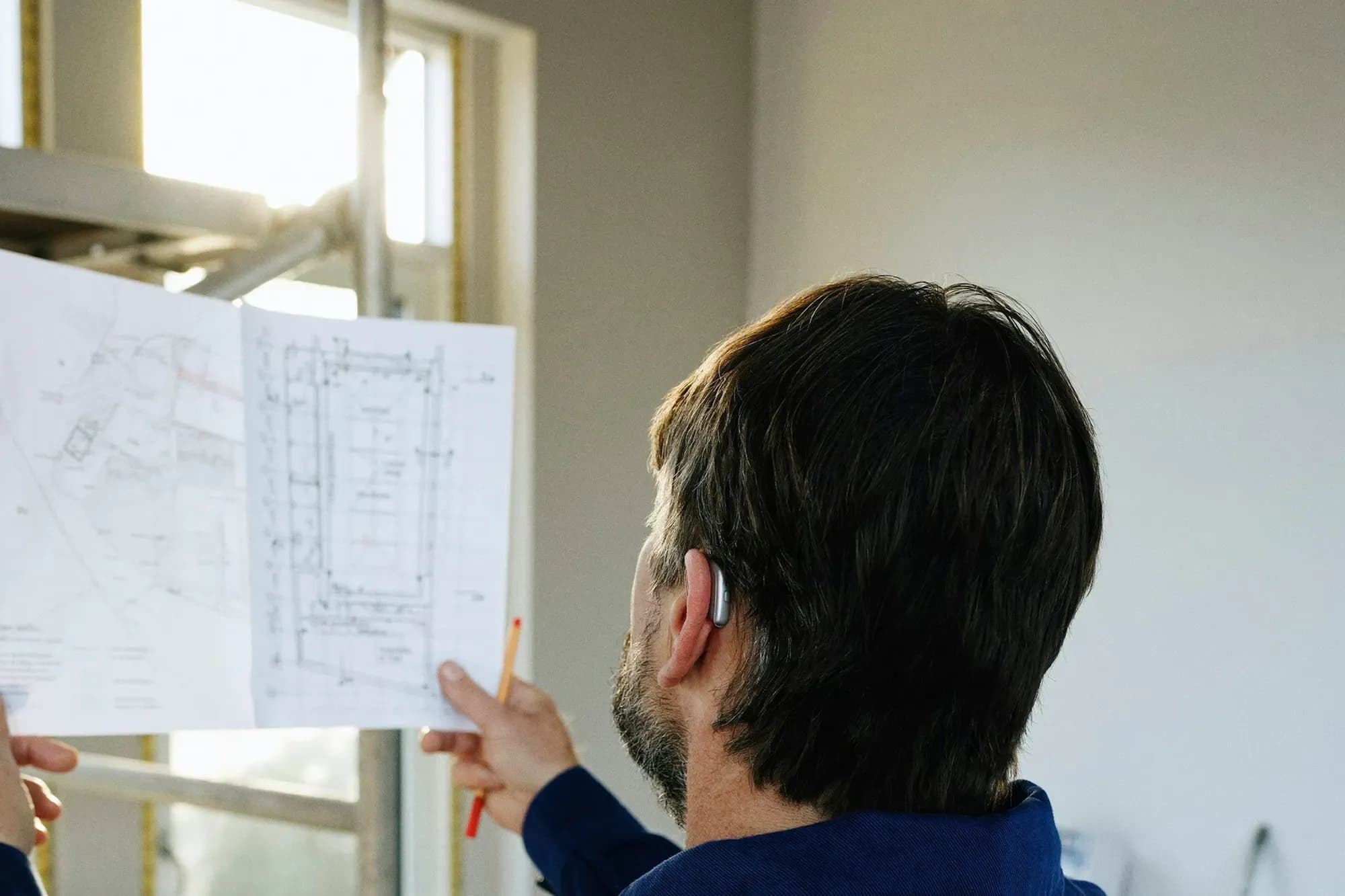 Engineer holding up a drawing against a window to check it on site