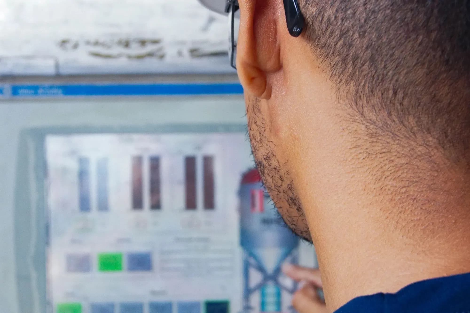 Engineer in a hard hat touching an industrial HMI panel that shows a process graphic and level bars